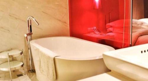 a bathroom with a white tub and a red wall at Jinjiang Metropolo Hotel Classiq Shanghai Off Bund in Shanghai