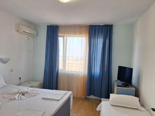 a bedroom with a bed and a window with blue curtains at Complex Exotica in Lozenets
