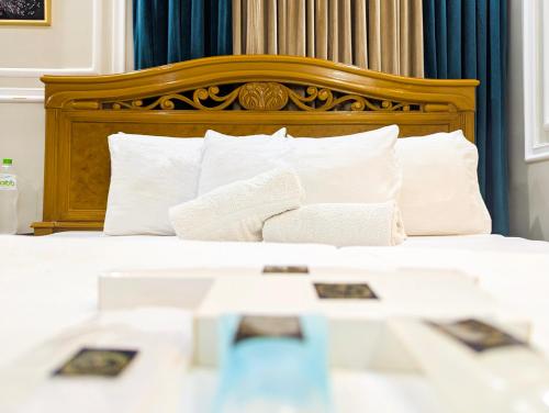 a bed with a wooden headboard and white pillows at Hotel StayInn - Airport Branch Karachi in Karachi