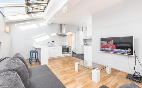 a living room with a couch and a tv on a wall at Apartment Zegadłowicza in Kraków