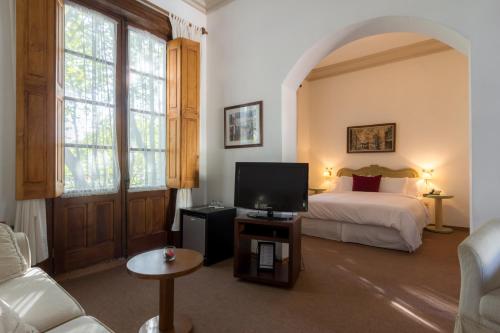 a bedroom with a bed and a tv in a room at Don Antonio Posada in Colonia del Sacramento