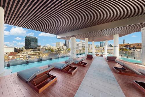 a rooftop pool with benches and a view of a city at Stylish 2BR with Story Bridge & Fireworks Views in Brisbane