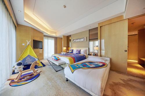 a hotel room with two beds and a baby crib at Hilton Dalian in Dalian