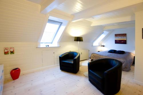 a bedroom with two chairs and a bed and a window at Den Gamle Købmandsgaard Bed & Breakfast in Ribe