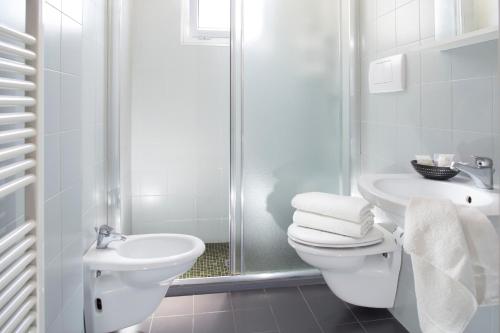 a white bathroom with a toilet and a sink at Club Meeting Hotel in Rimini