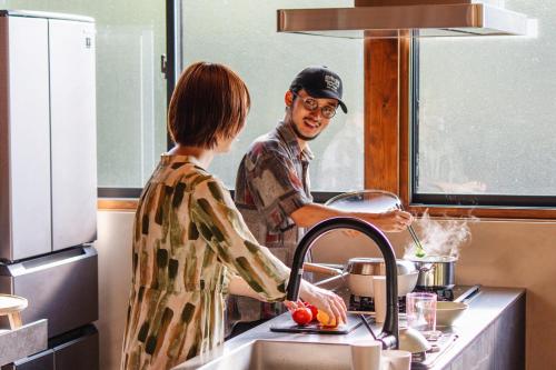 un homme et une femme debout dans une cuisine préparant la nourriture dans l'établissement Villa SCALA, à Sumoto