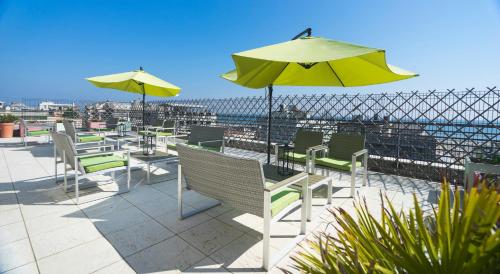 a patio with tables and chairs and an umbrella at Club Meeting Hotel in Rimini