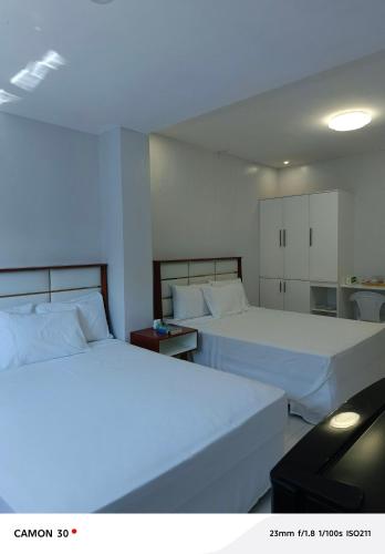 two beds in a hotel room with white sheets at EPM Tower Hotel and Events Place in Alfonso
