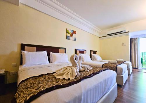 two beds in a hotel room with towels on them at Hotel Taiping Perdana in Taiping