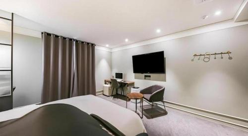 a bedroom with a bed and a desk and a tv at Cheongju Maryjane Hotel in Cheongju