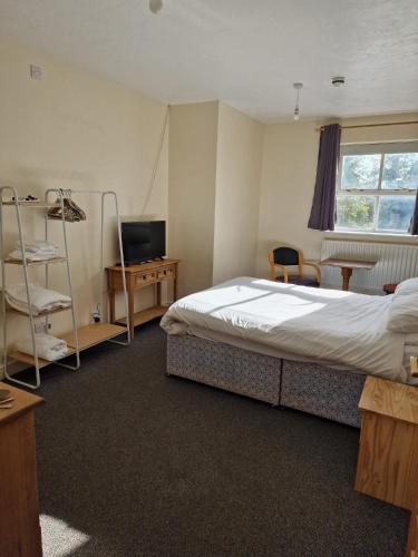 a bedroom with a bed and a desk and a television at OYO The Watermans Arms Hersham in Hersham