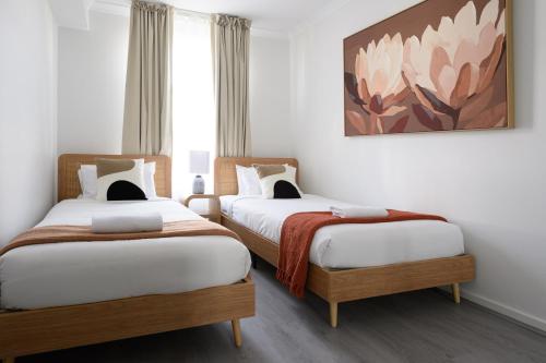 Dos camas en una habitación con un cuadro en la pared. en 104 EastPerth Euphoria Escape 2BR Parkng, en Perth