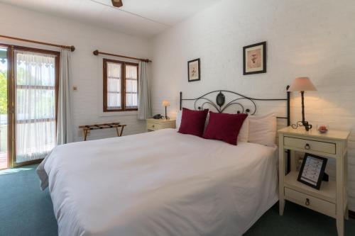 a bedroom with a large white bed with red pillows at Don Antonio Posada in Colonia del Sacramento