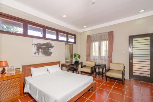 a bedroom with a bed and a desk and chairs at Mekong Long Thanh Resort & Reststop in Ấp Thanh Nguyên