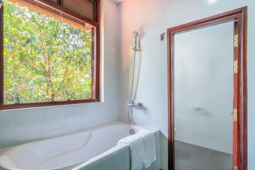 a white bath tub in a bathroom with a window at Mekong Long Thanh Resort & Reststop in Ấp Thanh Nguyên