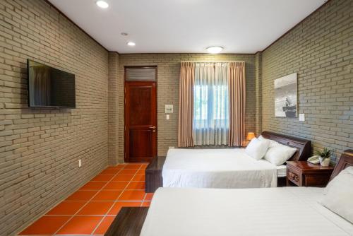 a hotel room with two beds and a tv at Mekong Long Thanh Resort & Reststop in Ấp Thanh Nguyên