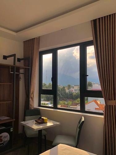 a room with a large window with a table and a desk at Hilaria Hotel in Vạn Ninh