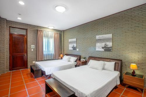 a bedroom with two beds and a brick wall at Mekong Long Thanh Resort & Reststop in Ấp Thanh Nguyên