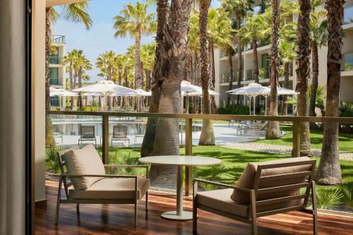 a balcony with chairs and a table and palm trees at Marriott Residences Salgados Resort, Algarve in Albufeira