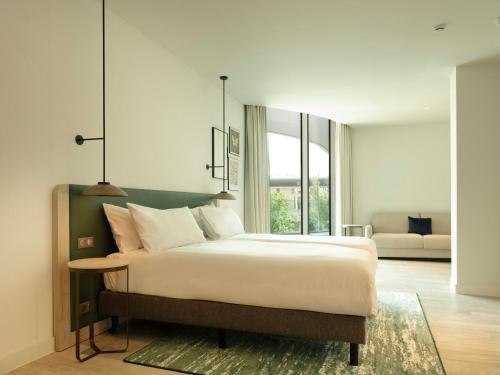a bedroom with a large bed with a table at Hilton Garden Inn Brussels Airport in Diegem