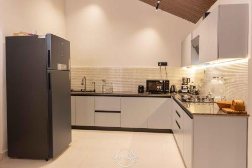 a kitchen with white cabinets and a black refrigerator at Villa Serendipity Aldona in Aldona