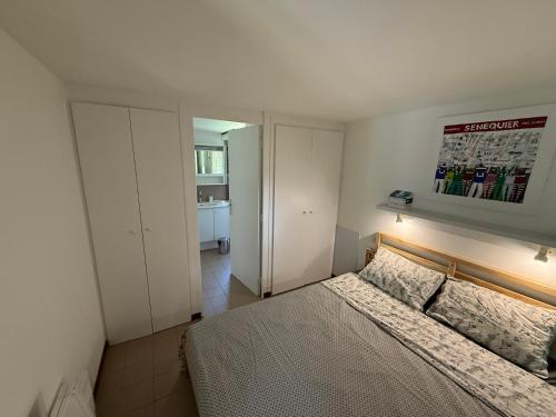 La petite maison في Saint-Martin-d'Uriage: غرفة نوم بها سرير ولوحة معلقة على الحائط