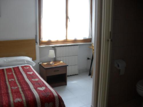 a bedroom with a bed and a table and window at Al Caminetto in Aosta