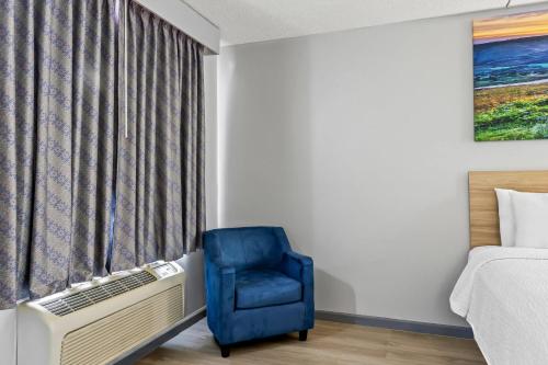 a room with a blue chair next to a window at Days Inn by Wyndham Salina South in Salina