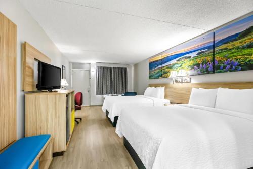 a hotel room with two beds and a flat screen tv at Days Inn by Wyndham Salina South in Salina