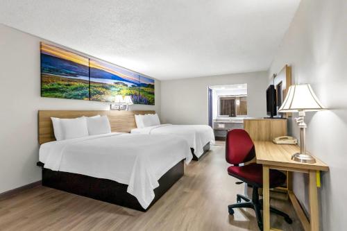 a hotel room with two beds and a desk with a chair at Days Inn by Wyndham Salina South in Salina