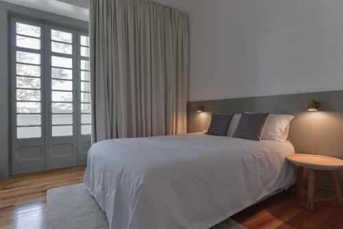a bedroom with a white bed and a table at Jardim do Embaixador Apartments by LovelyStay in Lisbon