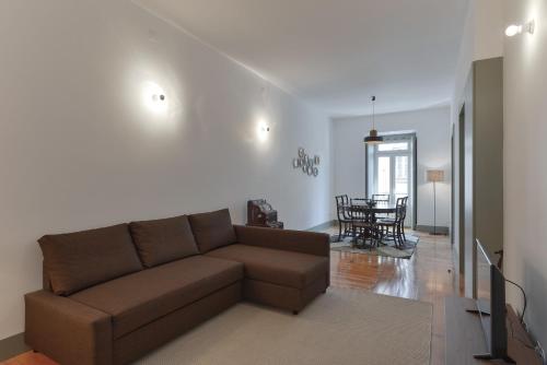 a living room with a brown couch and a dining room at Jardim do Embaixador Apartments by LovelyStay in Lisbon