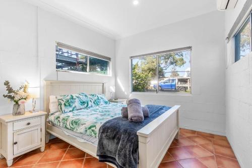 a bedroom with a bed and two windows at Boronia Avenue 18 in Mylestom