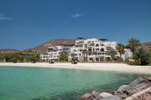 a white building on a beach next to the water at Playa de La Paz by Lumina in La Paz