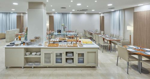 un restaurante con mesas y un mostrador con comida. en NH Valencia Las Ciencias, en Valencia