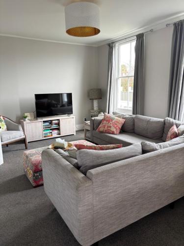 a living room with a couch and a flat screen tv at Luxury Village Villa 200metres from Village in Havelock North