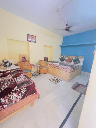 a bedroom with two beds and a table and chairs at Hotel Neem Haveli in Jaisalmer