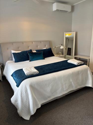 a bedroom with a large bed with blue pillows at Luxury Village Villa 200metres from Village in Havelock North