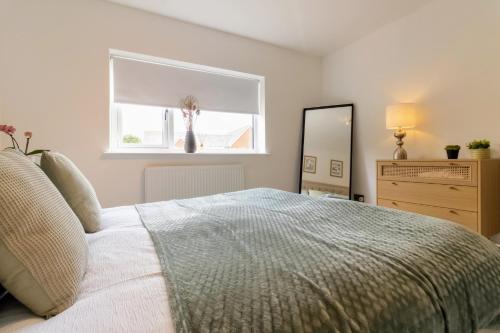 a bedroom with a large bed and a window at Stunning 4-bed Home in Milton Keynes by Renzo, Swimming Pool, Games Room! in Bletchley