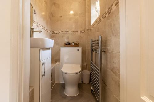 a small bathroom with a toilet and a sink at Stunning 4-bed Home in Milton Keynes by Renzo, Swimming Pool, Games Room! in Bletchley