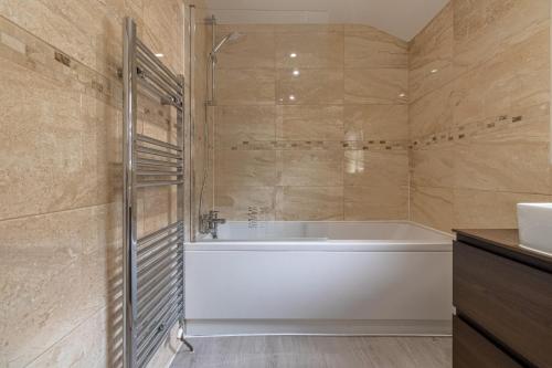 a bathroom with a tub and a sink at Stunning 4-bed Home in Milton Keynes by Renzo, Swimming Pool, Games Room! in Bletchley