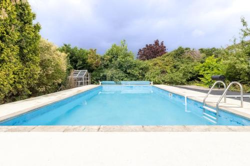 a swimming pool with blue water and trees at Stunning 4-bed Home in Milton Keynes by Renzo, Swimming Pool, Games Room! in Bletchley