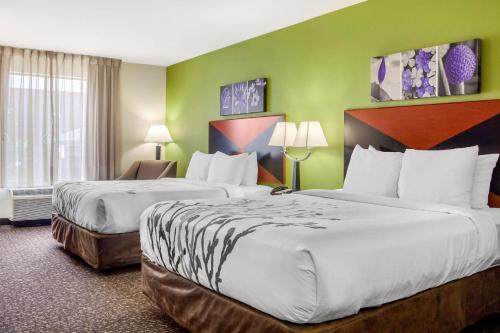 two beds in a hotel room with green walls at Sleep Inn & Suites Milwaukee Airport in Milwaukee