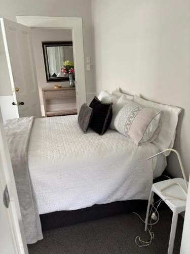 a bedroom with a large white bed with pillows at Luxury Village Villa 200metres from Village in Havelock North