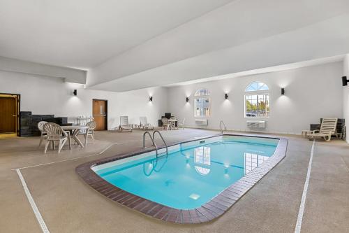 a swimming pool in a room with a table and chairs at Rodeway Inn Rapid City North in Rapid City