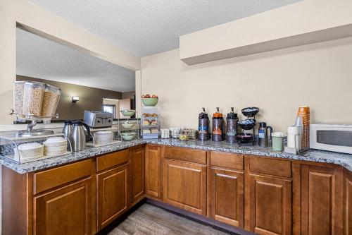 a kitchen with wooden cabinets and a counter top at Rodeway Inn Rapid City North in Rapid City