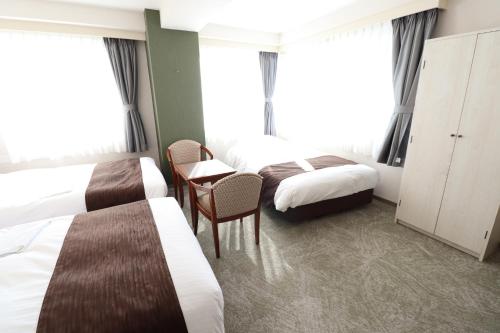 a hotel room with two beds and a table and chairs at Imabari Urban Hotel in Imabari