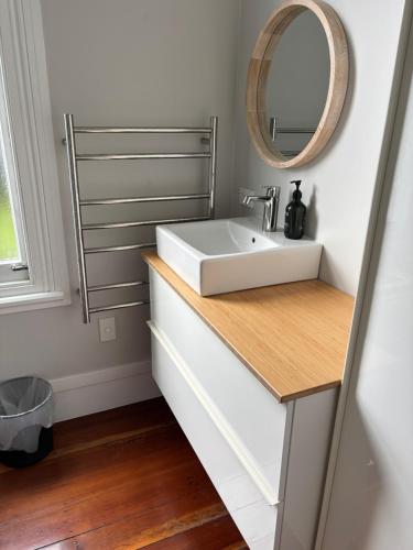 a bathroom with a white sink and a mirror at Luxury Village Villa 200metres from Village in Havelock North