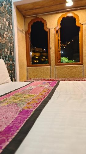 a bedroom with two windows and a bed with a rug at Hotel Fort View -The Heart of city in Jaisalmer