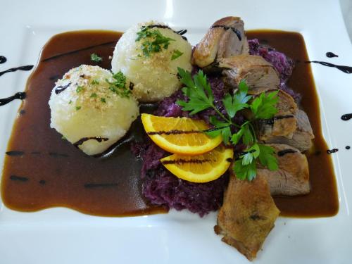 a plate of food with meat and mashed potatoes and orange slices at Hotel zur Kanone in Tautenhain